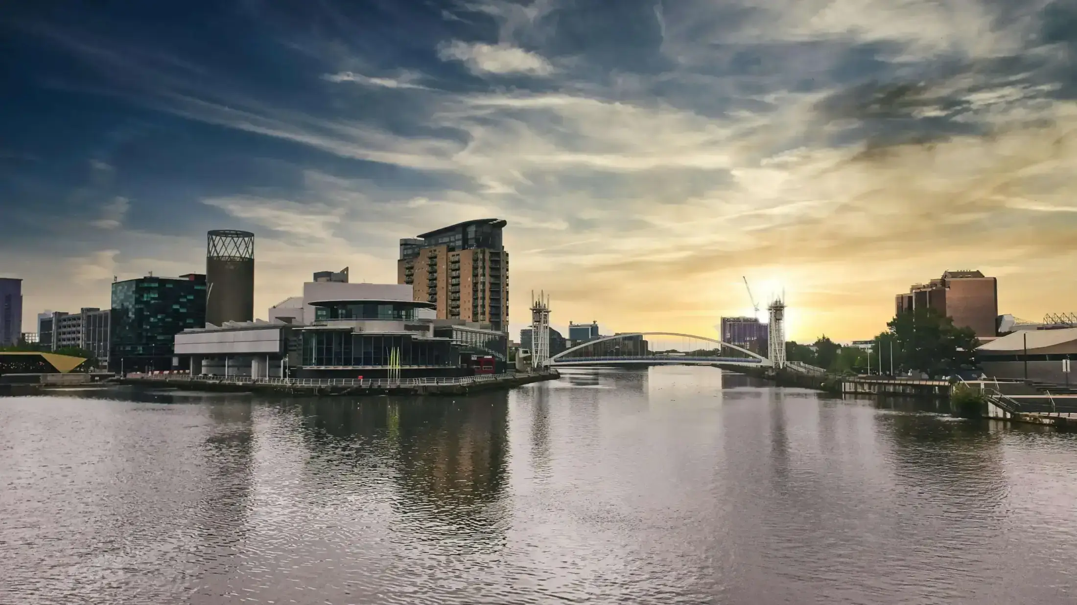 Sunset over modern buildings and bridge at Salford Quays.