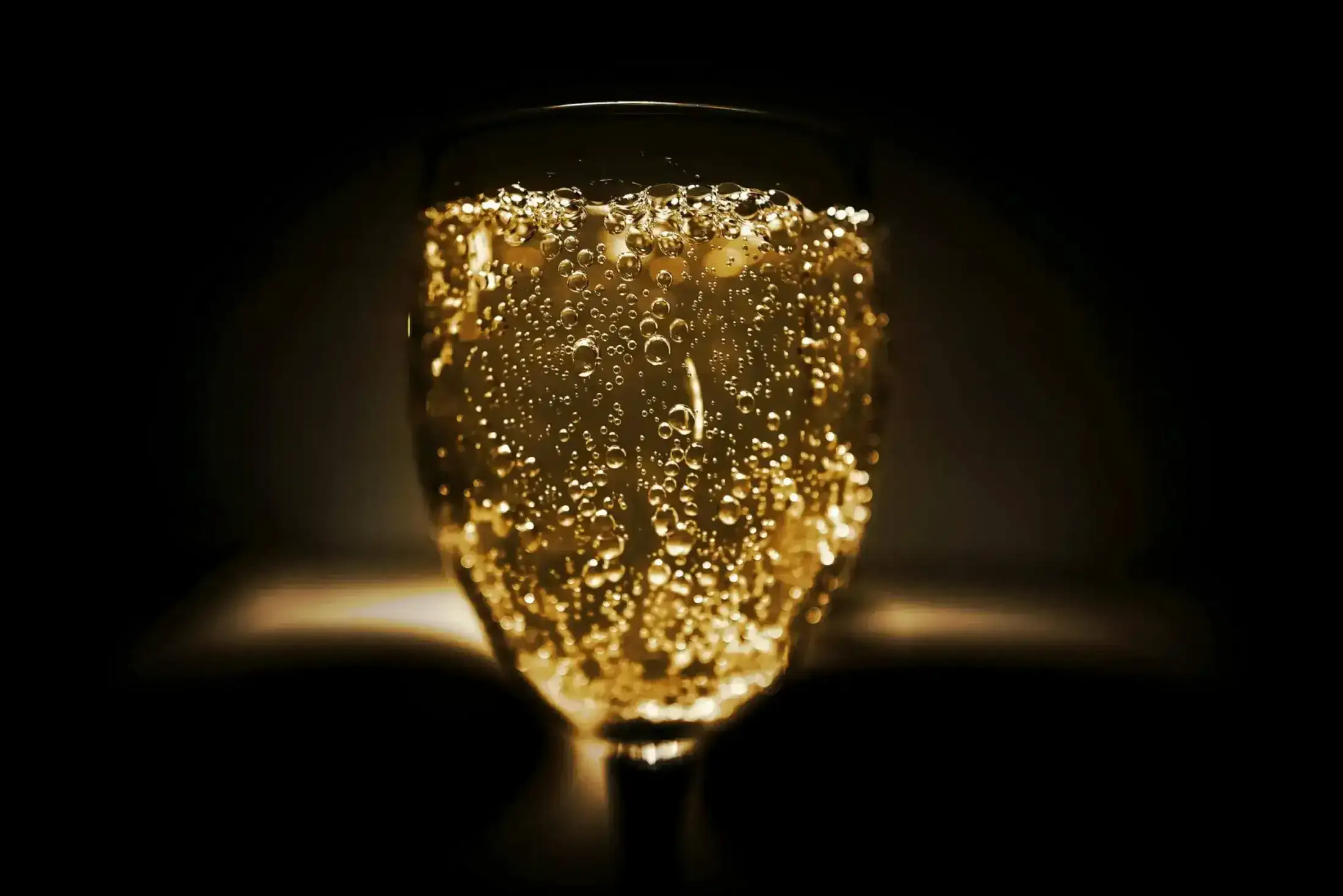 Close-up of golden champagne bubbles in a glass.