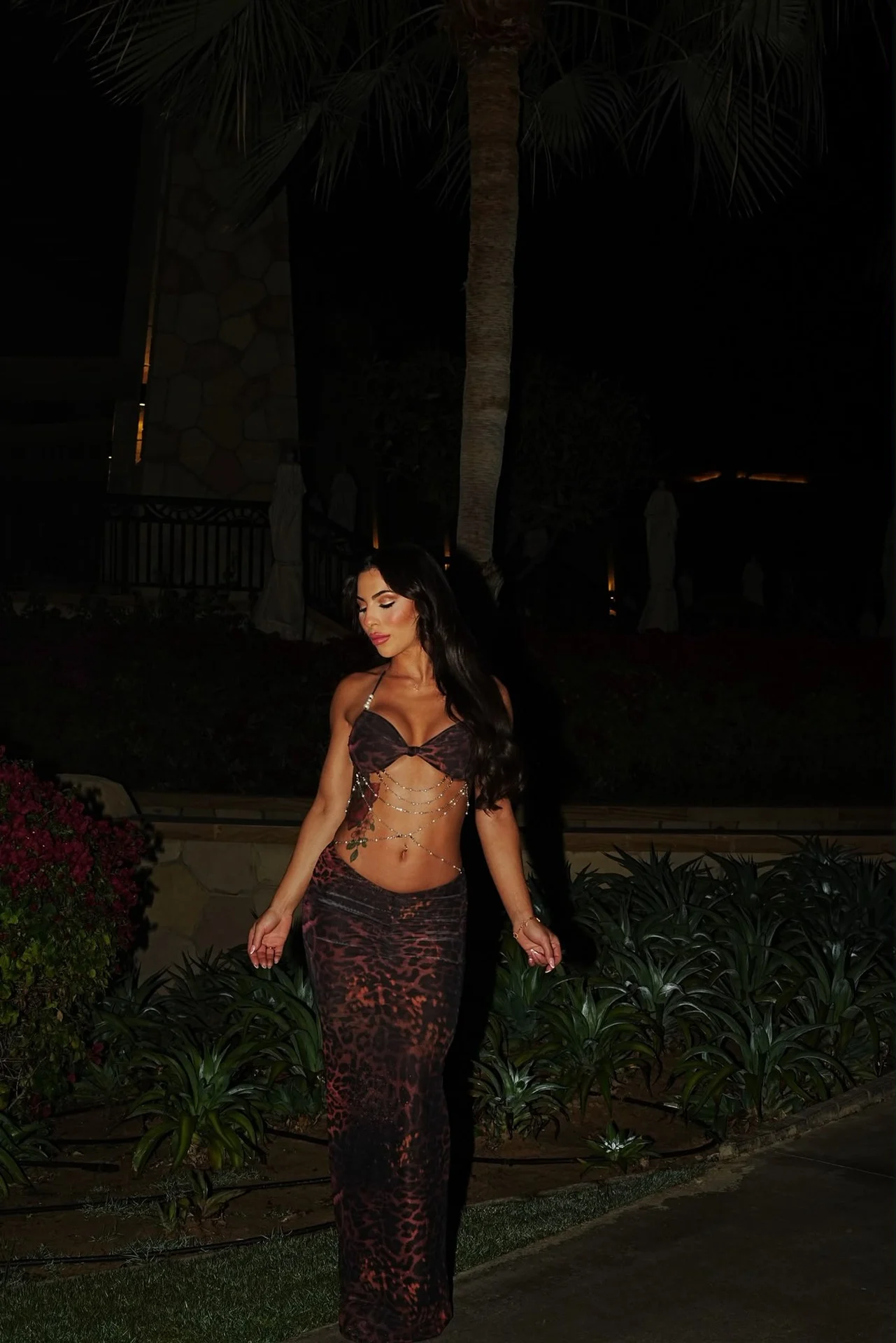 Woman in a leopard print skirt and top at night.