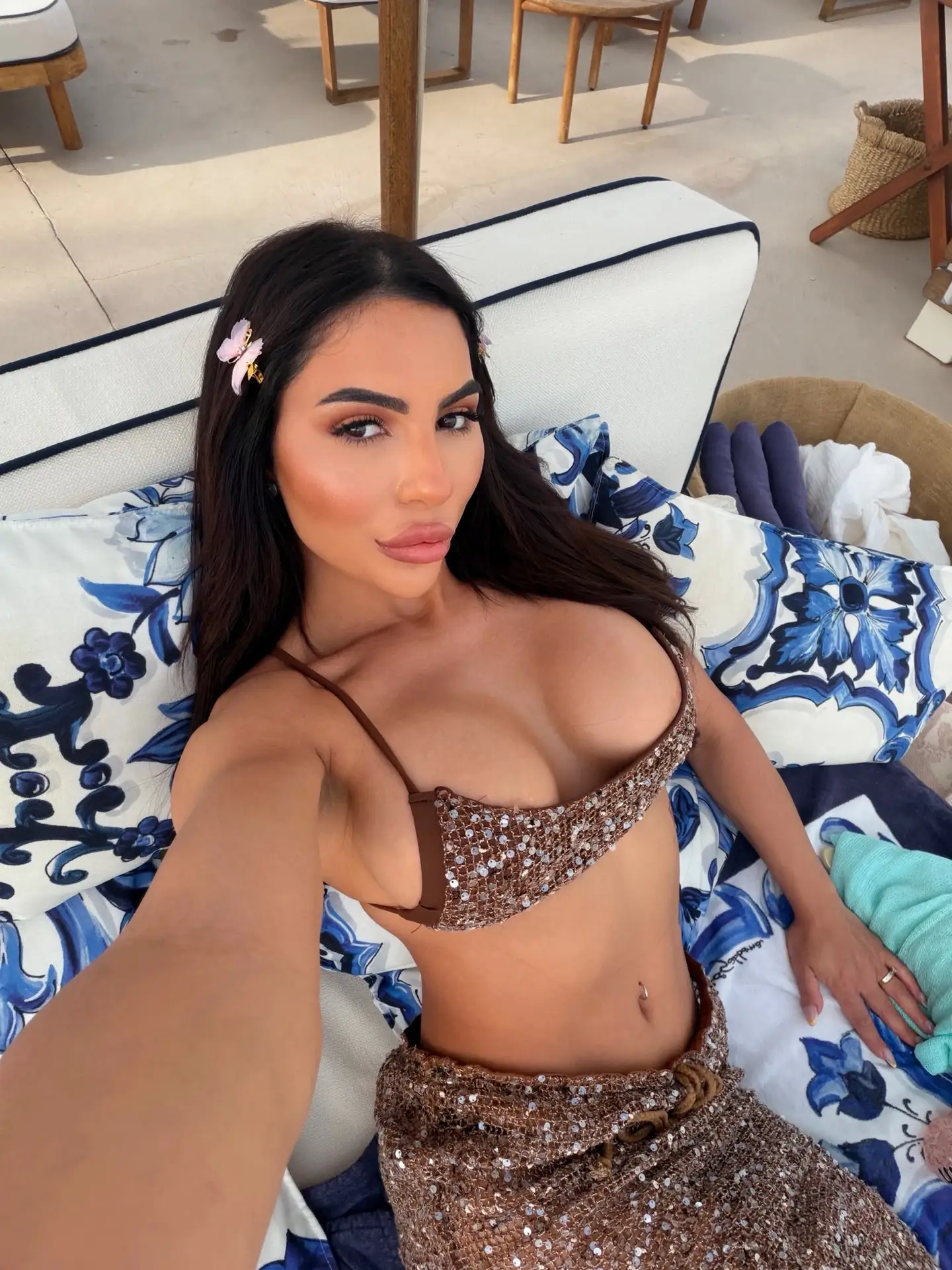 Woman wearing a brown sequinned bikini reclining on a sun lounger.