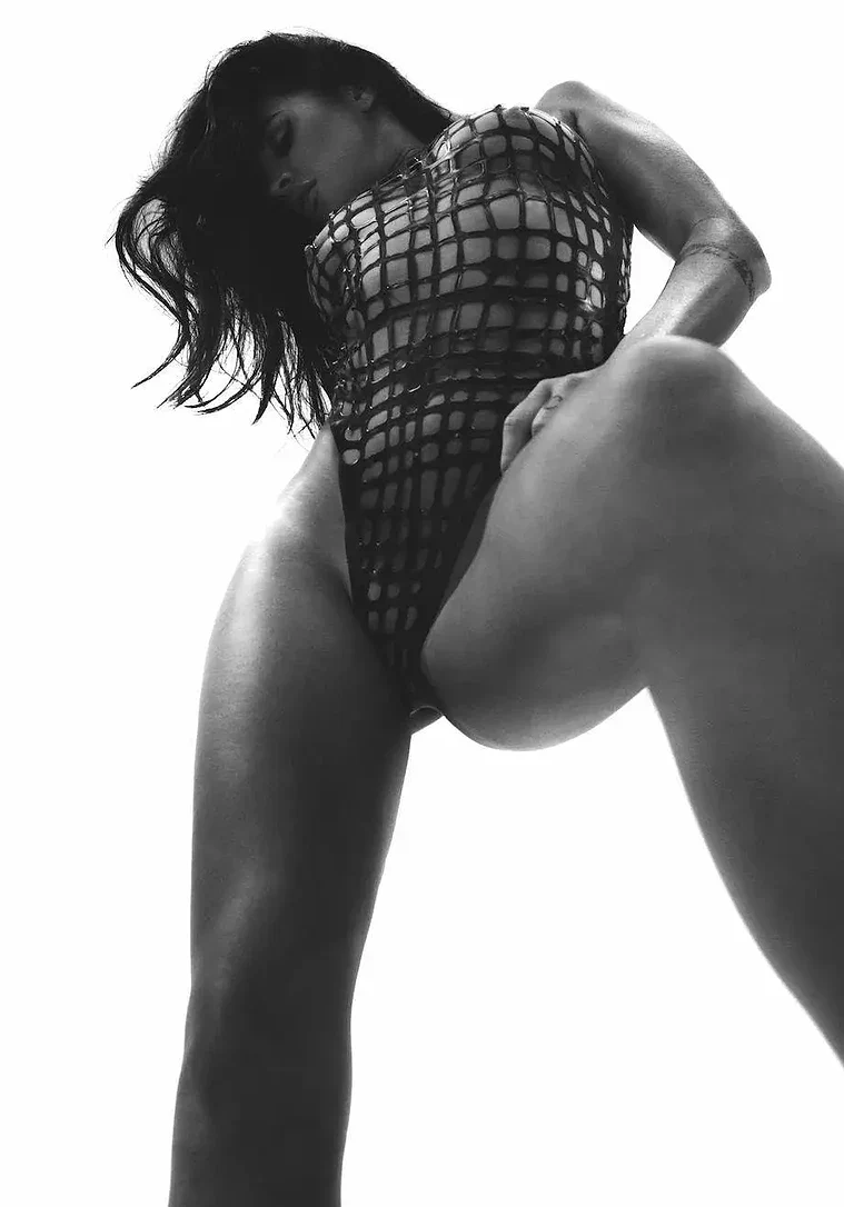 Misstress Freya, escort - Artistic monochrome low-angle shot of a woman in fishnet bodysuit.