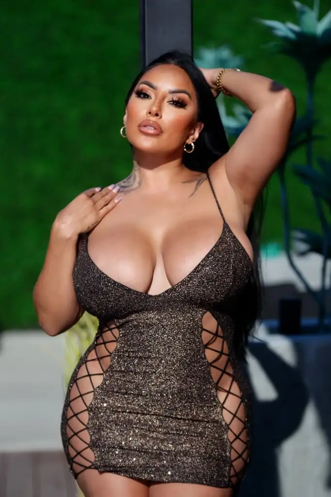Woman in a shimmering gold cut-out dress posing.