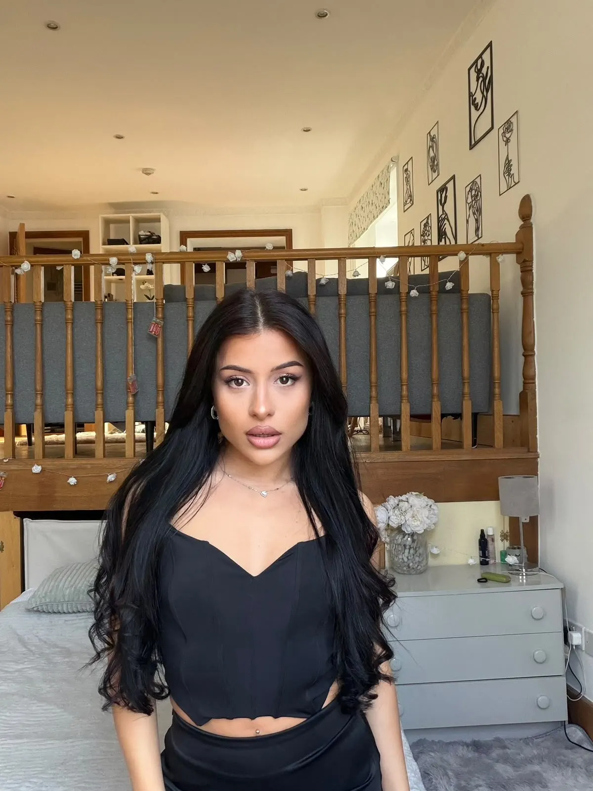 A woman with long black hair in a modern bedroom.