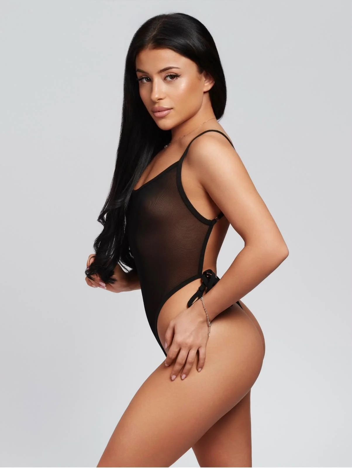 Woman posing in a black sheer mesh bodysuit.