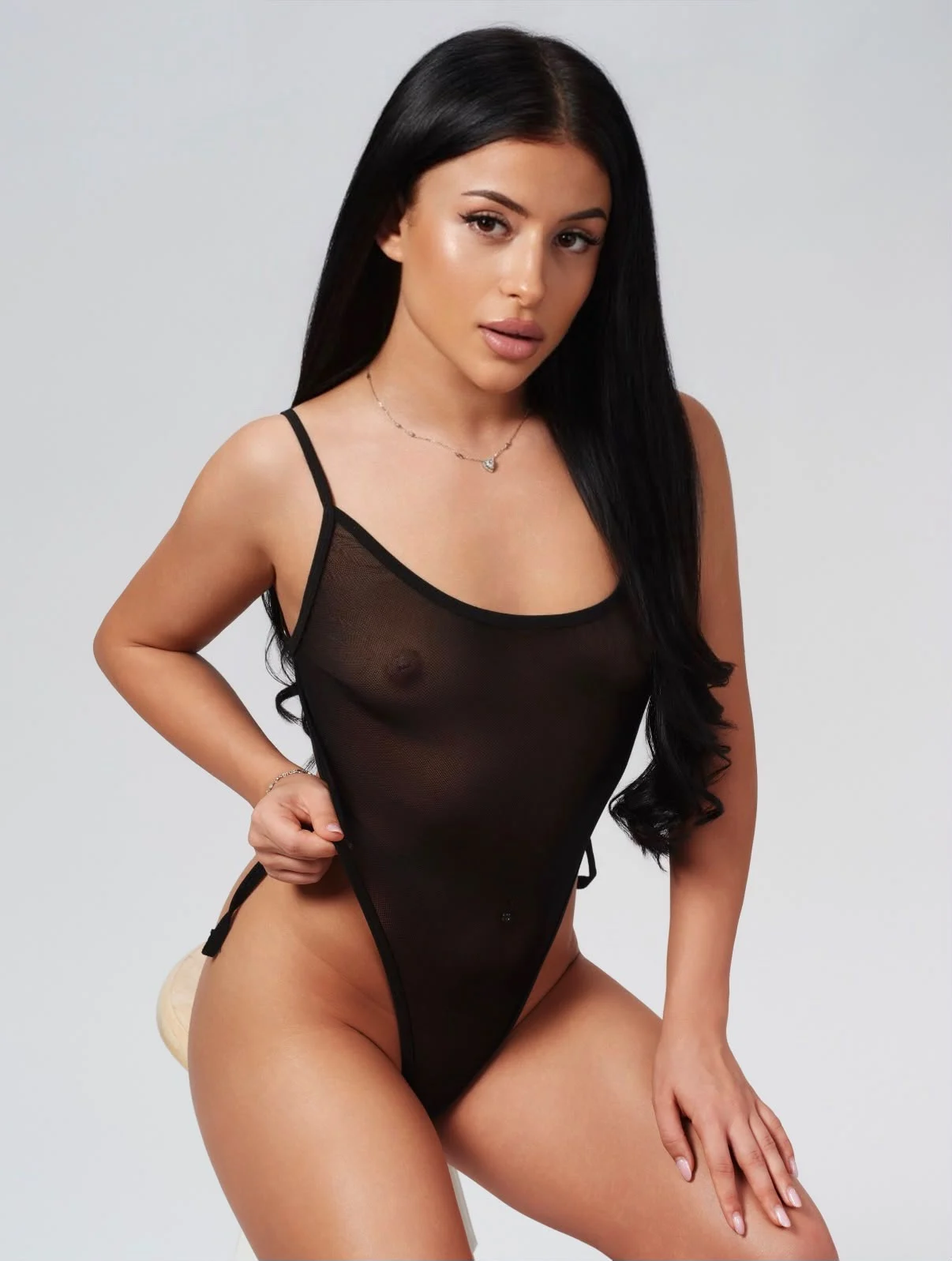 Woman with long dark hair wearing a sheer black bodysuit